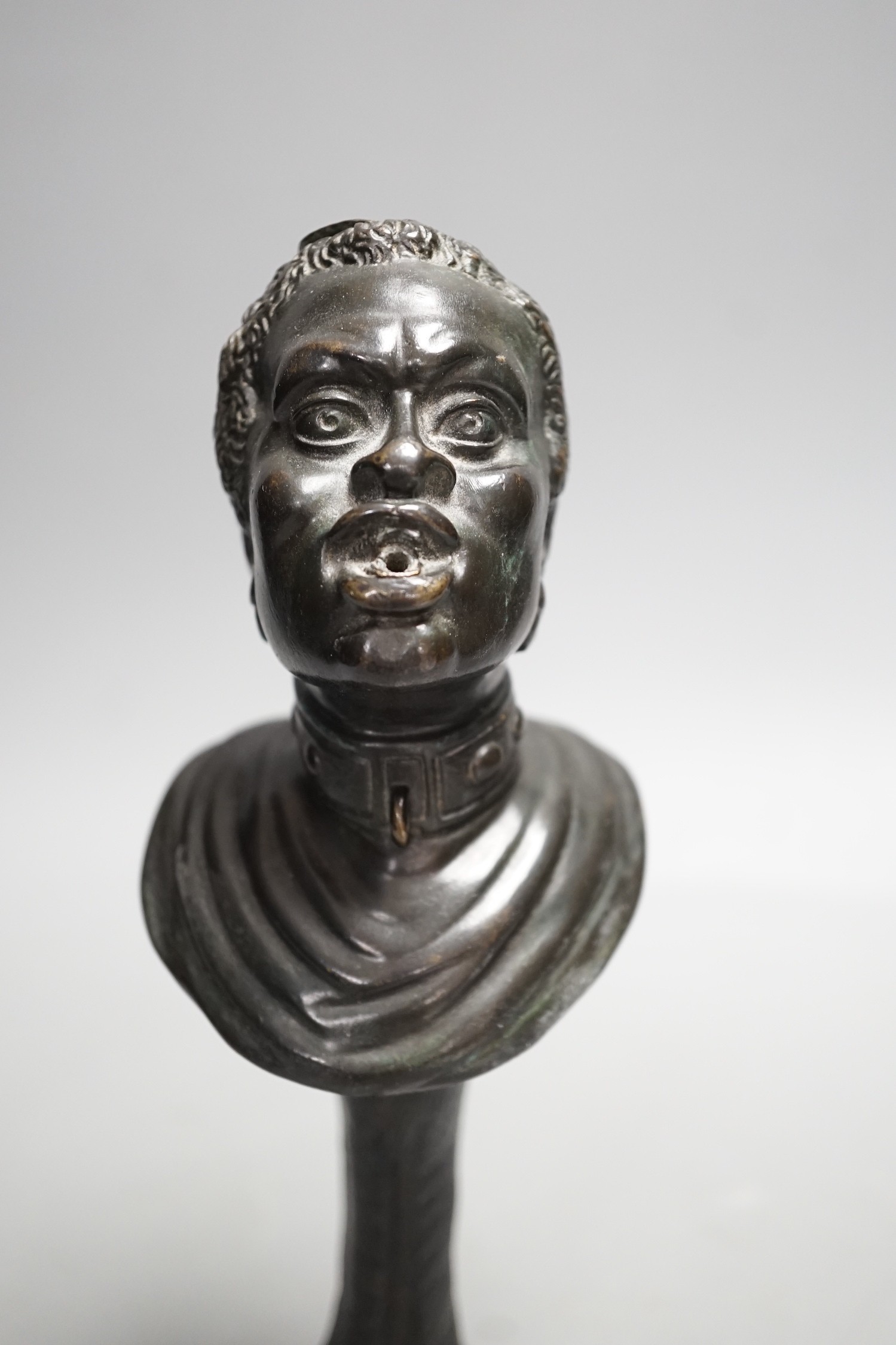 A bronze slave portrait bust on claw stand. 23cm high